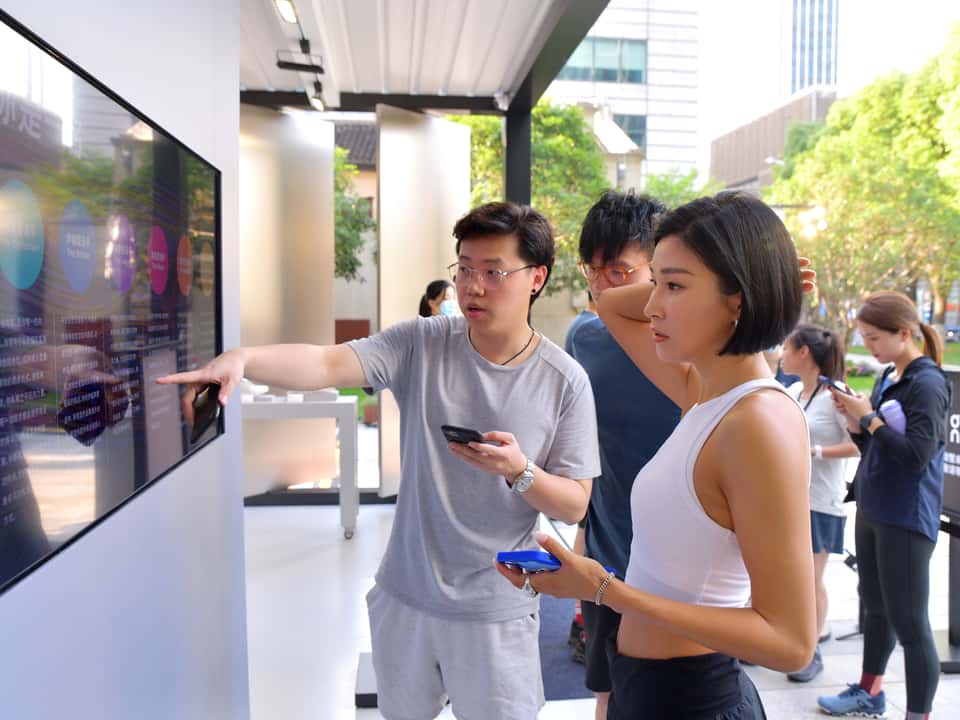 People looking at the run scan results on a monitor mounted on a wall in an On Running store.
